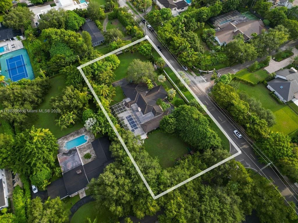 Screened pool and covered patio with lounge chairs and palms at a Pinecrest home